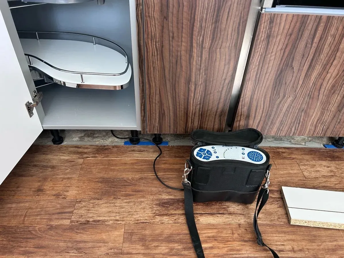Tracer gas detector on the floor in front of kitchen units with the kick-board removed
