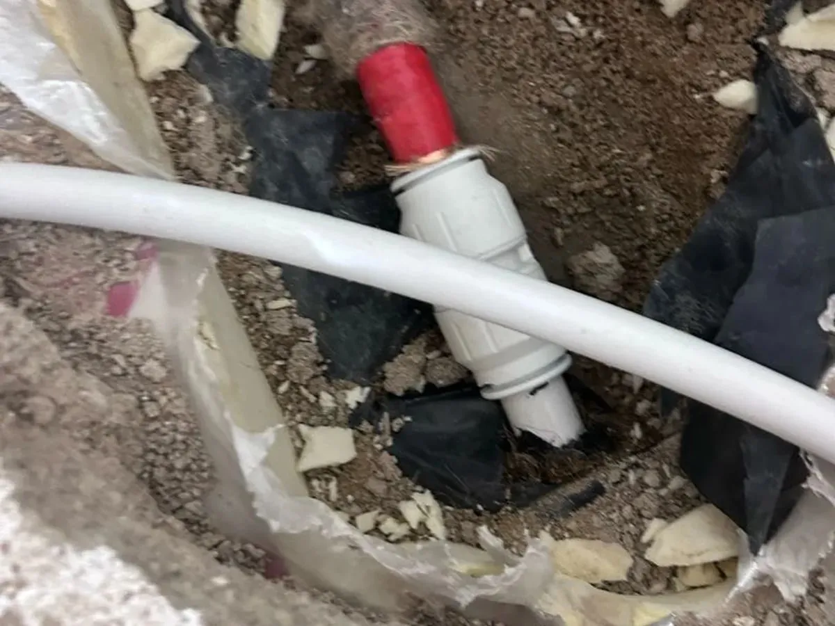 White plastic pipe with a push-fit coupling in an opened hole in the floor