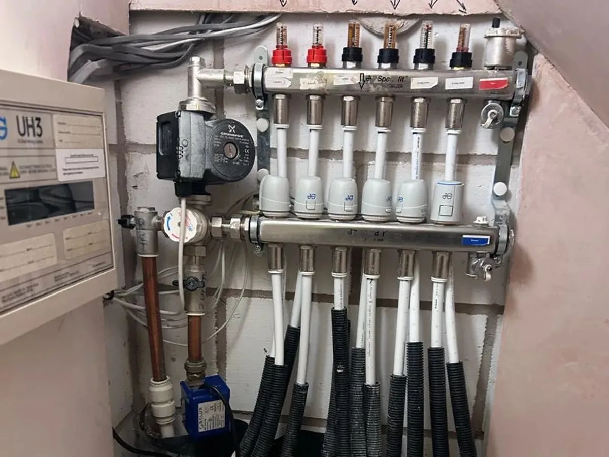 Underfloor heating manifold with a row of circuits and a pump in a cupboard